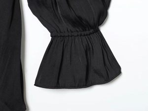 Detail of elegant black ruffled elastic cuffs on smooth satin long sleeve dress