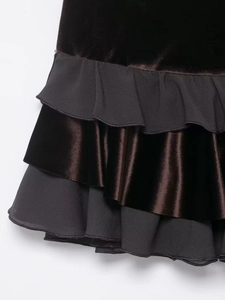 Detailed close-up of layered ruffles on velvet and chiffon fabric in dark brown