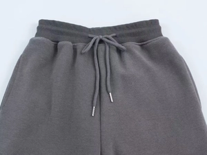 Detail of dark grey ribbed sweatpants featuring elastic waist and metal-tipped drawstrings
