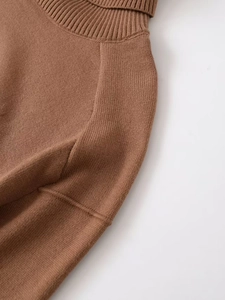 Close-up of caramel brown knit sweater featuring ribbed turtleneck and shoulder seam details