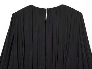 Detail view of black pleated dress featuring a back cutout with a single button closure