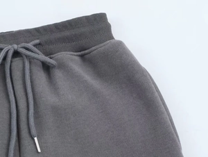 Detail of dark grey ribbed elastic waistband with drawstring and silver metal tips