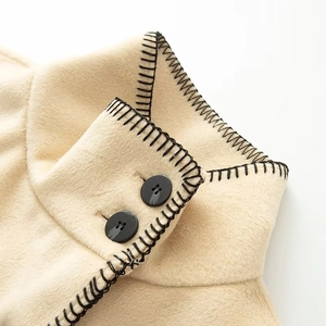 Women's turtleneck wool coat in light apricot with black whipstitch edges and buttons