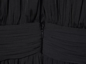 Close-up of elegant pleated waist design and invisible zipper on black long-sleeve dress