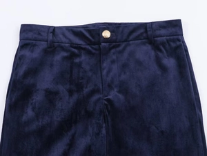 Detail of dark blue velvet trousers showing waist belt loops and gold embossed metal button