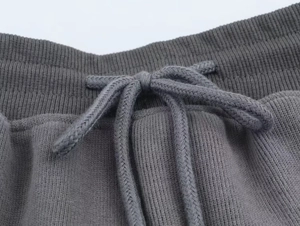 Detail shot of grey ribbed elastic waistband and woven drawstring on casual trousers