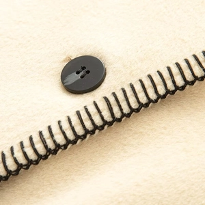 Macro shot of minimalist wool coat with blanket stitch edge and black button detail