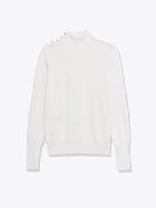 Close-up of a white knit top with elegant gold button accents on the shoulder
