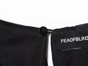 Detail of black dress neckline with round button closure and elastic loop fastening