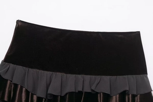 Macro view of high-waist velvet mini skirt featuring ruffled trim detail on brown fabric