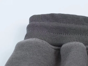 Detail of ribbed knit texture and elastic waistband on dark grey lounge trousers