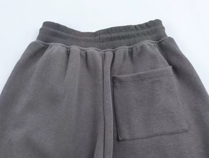 Detailed view of elastic waistband and back pocket on charcoal ribbed knit trousers