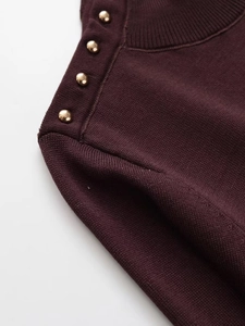 Detail of burgundy knit top showing the ribbed crew neck and golden rivet buttons