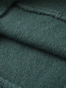 Close-up of deep green knit fabric showing soft texture and premium ribbed material