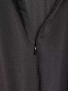 Detail shot of a black crepe dress featuring a seamless invisible teardrop zipper