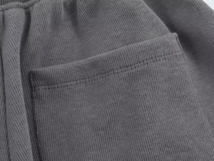 Detailed macro shot of stitching and knit texture on dark gray ribbed trousers