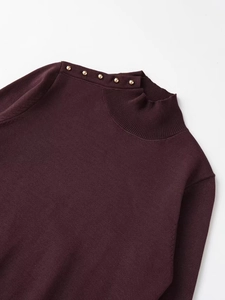 Detailed macro view of burgundy knit sweater featuring gold rivet buttons on the shoulder