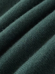 Macro shot of dark green knit fabric detail with soft texture and premium wool blend weave