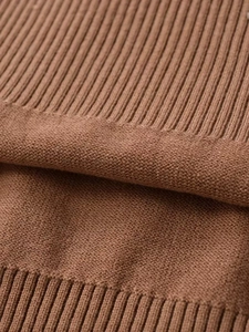 Macro texture of caramel knit sweater showing flat stitch and ribbed cuffs detail