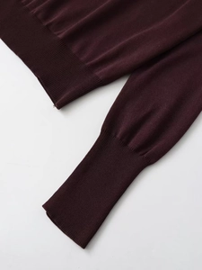 Detail of dark purple knit sweater showing fine texture and ribbed cuffs