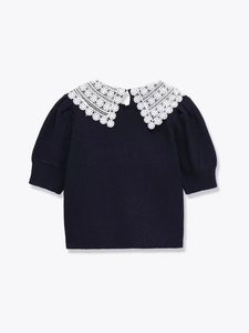 Detail of navy knit top with white oversized lace collar and subtle puff sleeves