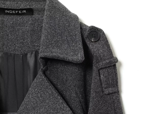 Macro detail of charcoal wool coat featuring shoulder epaulettes and branded inner lining