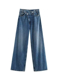 Détail d'un jean large à taille haute avec taille croisée asymétrique et délavage bleu