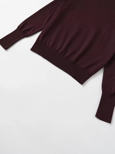 Detail view of burgundy knit sweater showing ribbed hem and sleeve cuffs texture