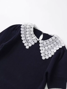 Detailed close-up of dark blue knit sweater featuring an oversized white lace Peter Pan collar