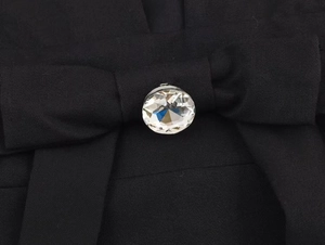 Gros plan du nœud noir avec un grand cristal à facettes sur le détail de la robe