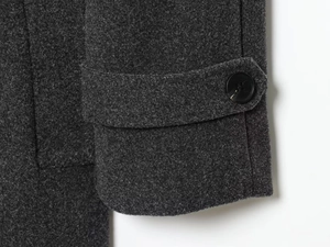 Close-up of dark grey wool coat cuff with adjustable strap and polished black button