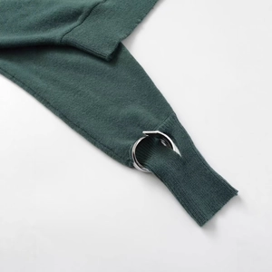 Dark green knit sweater sleeve with designer silver metal ring detail and texture