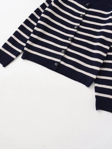 Dettaglio cardigan in maglia a righe blu e bianche con bottoni scuri e polsini a coste
