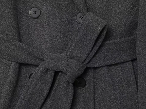 Detail of dark grey wool coat showing high-quality fabric texture and belted waist