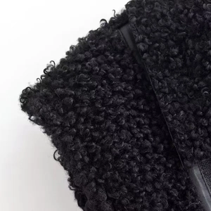 Gros plan sur la texture bouclée en fausse fourrure noire d'un gilet chaud