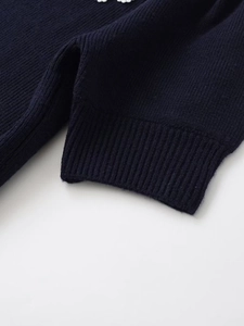 Detailed close-up of ribbed cuffs on a navy blue knitted sweater for autumn fashion