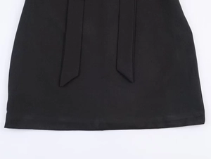 Détail de l'ourlet de robe noire avec rubans à nœuds montrant la texture du tissu tisse