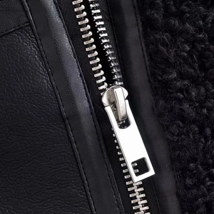 Détail de la fermeture éclair en métal argenté sur un gilet en cuir noir avec sherpa