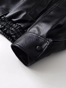 Detail of black pebbled leather jacket showing buttoned cuffs and elasticated hemline