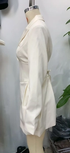 Detail view of cream tailored blazer dress featuring cinched waist and peak lapels