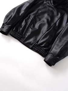 Detailed close-up of the black pebble faux leather jacket hem and snap button cuffs