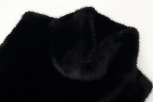 Close-up detail of luxurious black faux fur texture on sleeveless turtleneck top