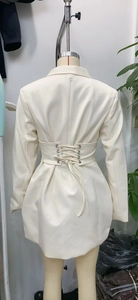 Detail of waist-cinching lace-up back design on a beige elegant blazer dress