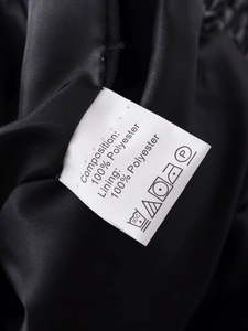 Close-up of internal wash care label showing 100% polyester composition on black jacket
