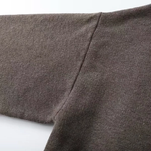 Gros plan détaillé des coutures d'épaule en maille marron foncé et texture du manteau court