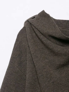Close-up of dark brown knit coat featuring asymmetric draped neckline and fine texture