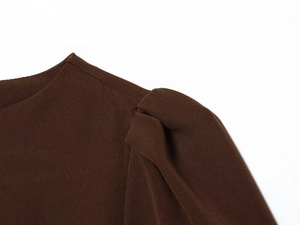 Gros plan détaillé sur l'épaule plissée et le tissu marron foncé d'une mini robe