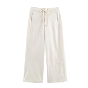 Dettaglio dei pantaloni larghi crema con vita elastica e coulisse regolabile