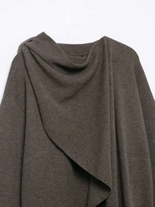 Detail of deep brown knit fabric showing soft draped neckline and premium wool texture