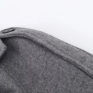 Détail de l'épaule d'un manteau en laine gris avec épaulette et bouton noir mat